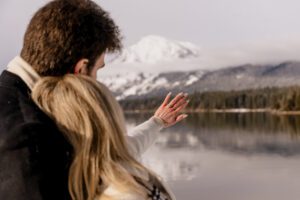 A newly engaged couple admires the engagement ring against the mountain backdrop