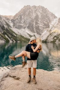 Man lifts his new fiancé during their engagement portraits at Colchuck Lake