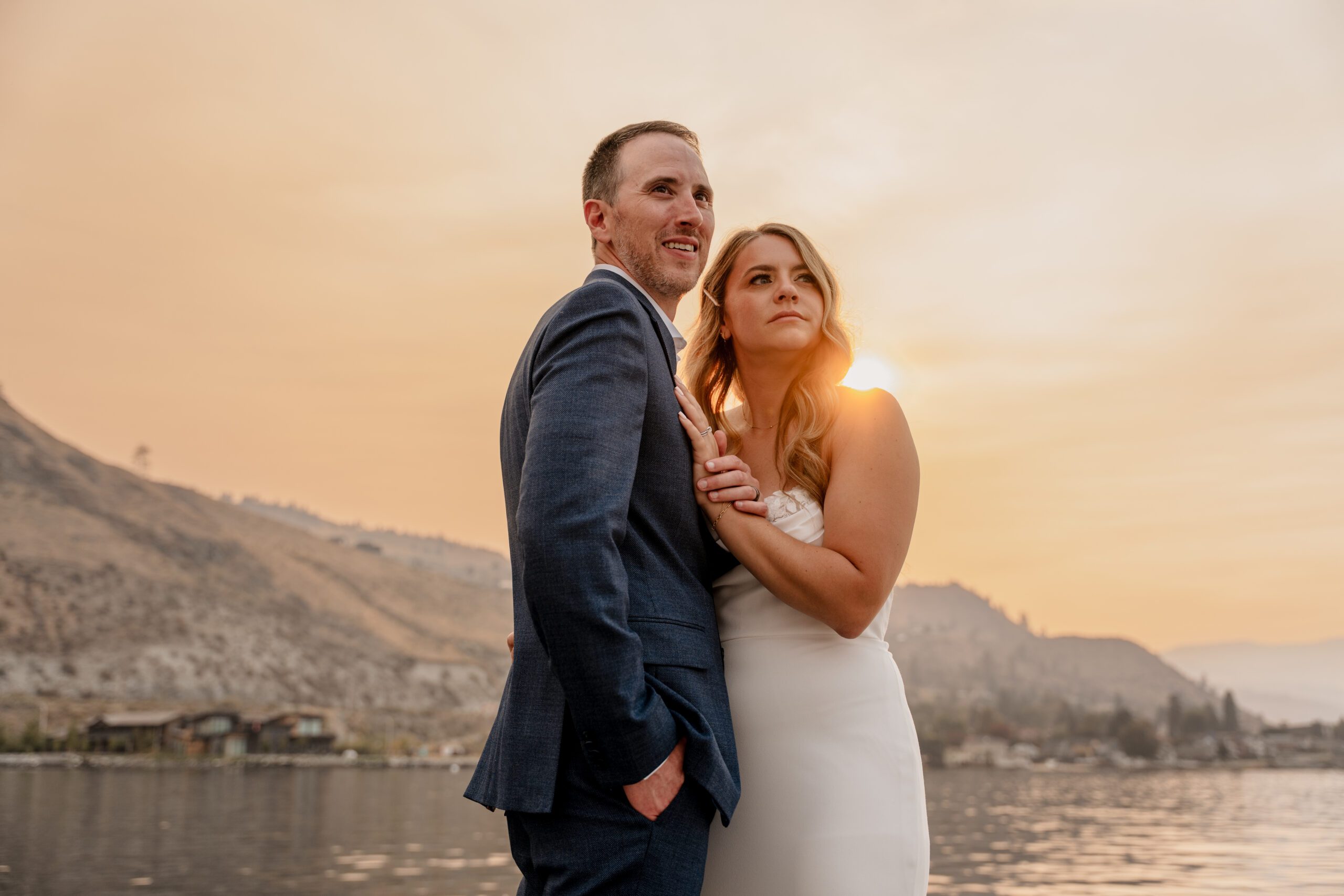 A bride and groom look out at the smoky sunset on their wedding day