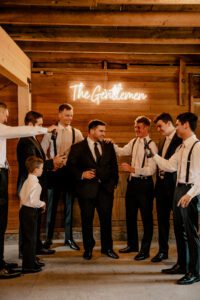 Groom getting ready with his groomsmen in the boys' getting ready suite at Machias Meadows wedding venue